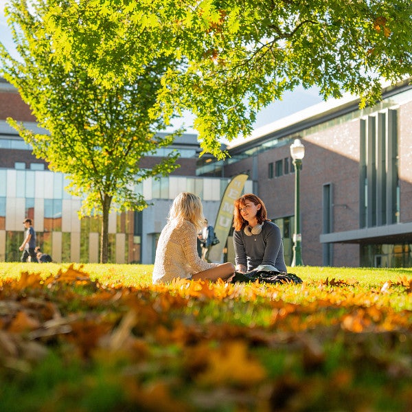 students sitting on UO campus lawn in fall