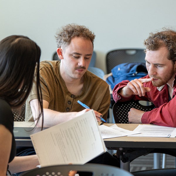 three students working on homework in classroom